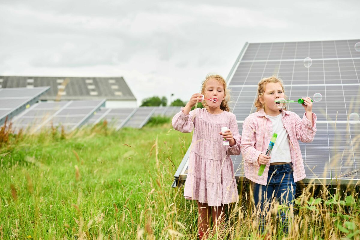 Twee jonge meiden staan op zonnepark Vierverlaten en blazen bellen. Fotograaf: Ronald Zijlstra.